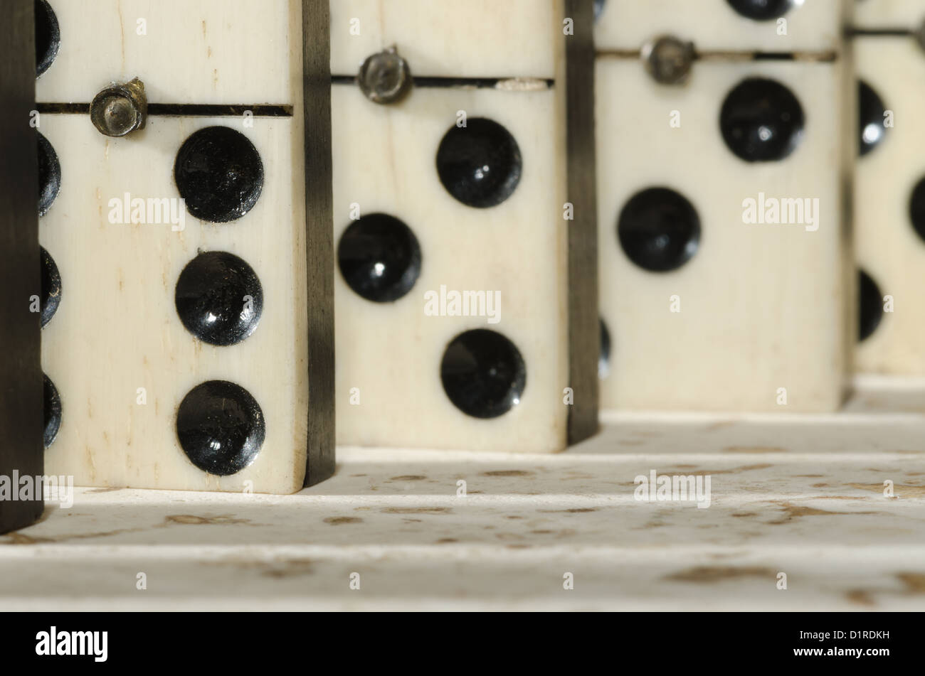 Reihen von aufgereiht altes Elfenbein und Ebenholz Bronze angehefteten stehende Domino blockiert Stücke auf weißem Tan Travertin-Marmor Stockfoto