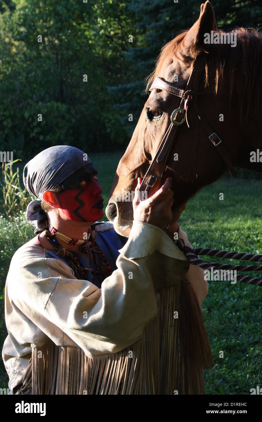 Ein Native American Indian Mann mit roter Bemalung hält sein Pferd. Stockfoto