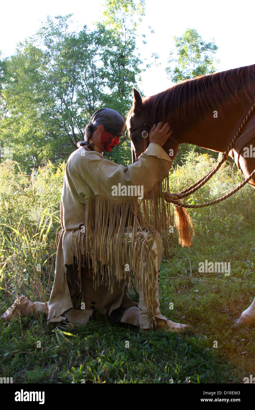 Ein Native American Indian Mann mit roter Bemalung Gruß sein Pferd. Stockfoto