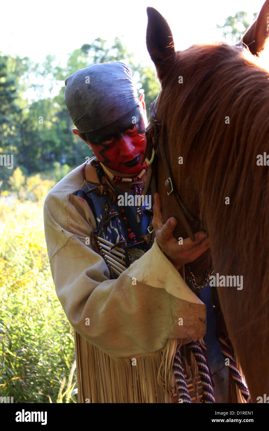 Ein Native American Indian Mann mit roter Bemalung Gruß sein Pferd. Stockfoto