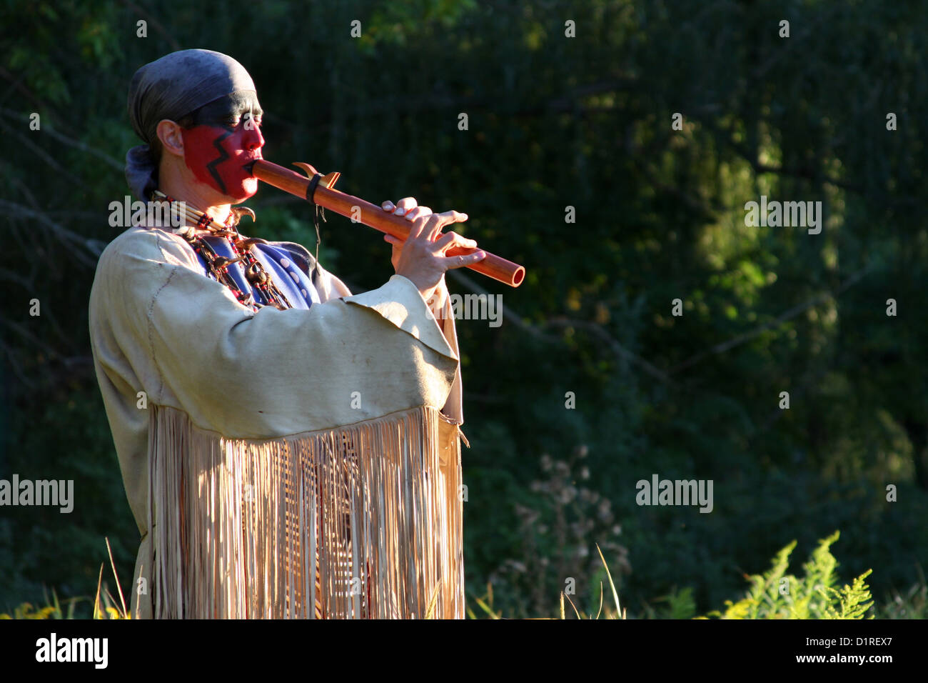 Ein Native American Indian Mann Flötenspiel draußen in der Natur Stockfoto