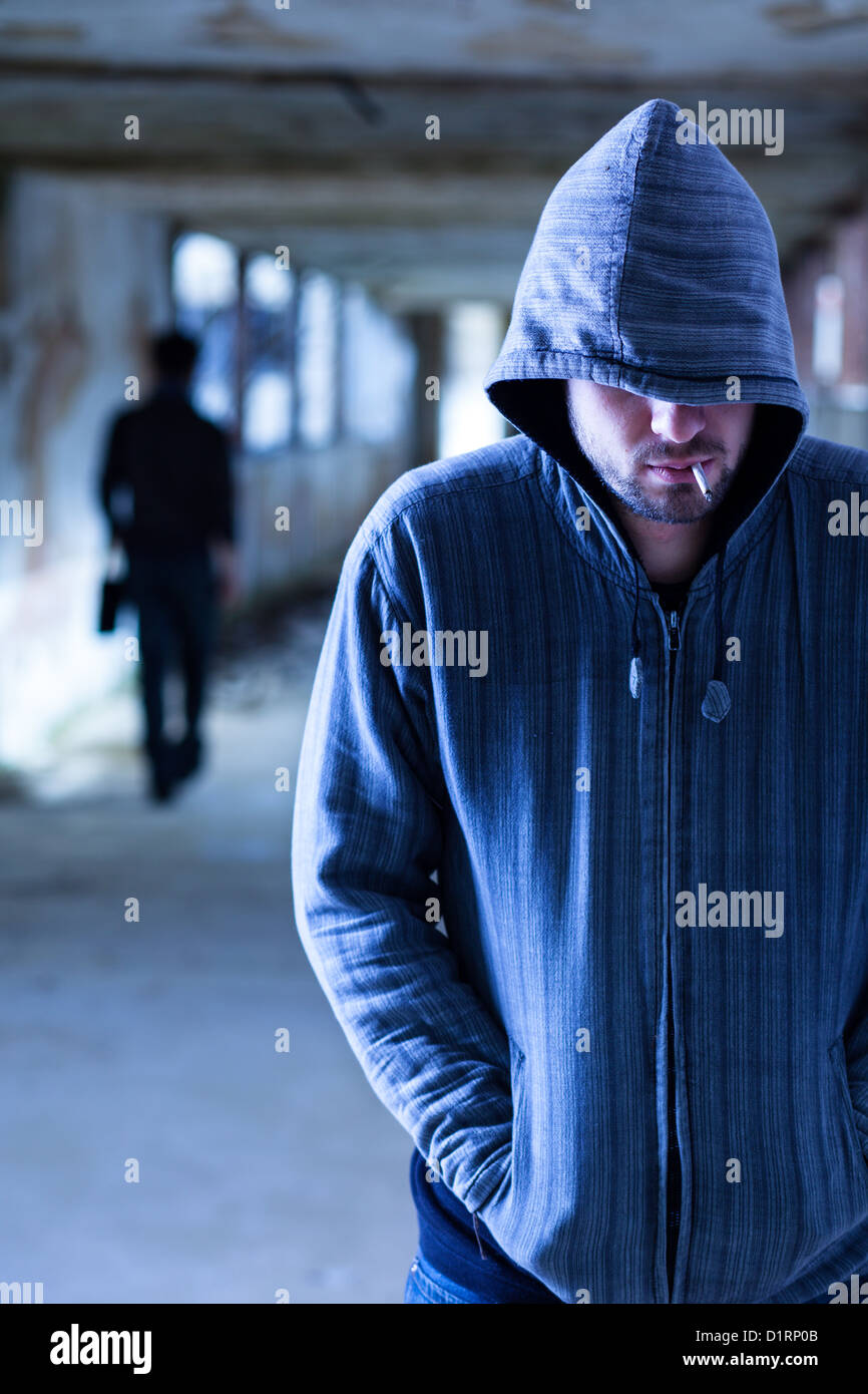Rauchen-Verbrecher mit Kapuze zu Fuß in einem Slum-Korridor Stockfoto
