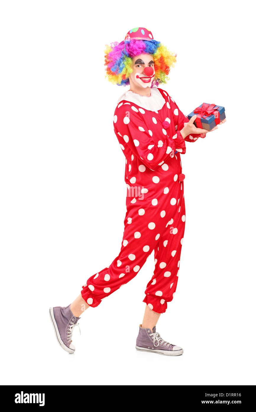 In voller Länge Portrait eines männlichen Clowns mit freudigen Ausdruck auf seinem Gesicht hält ein Geschenk isoliert auf weißem Hintergrund Stockfoto