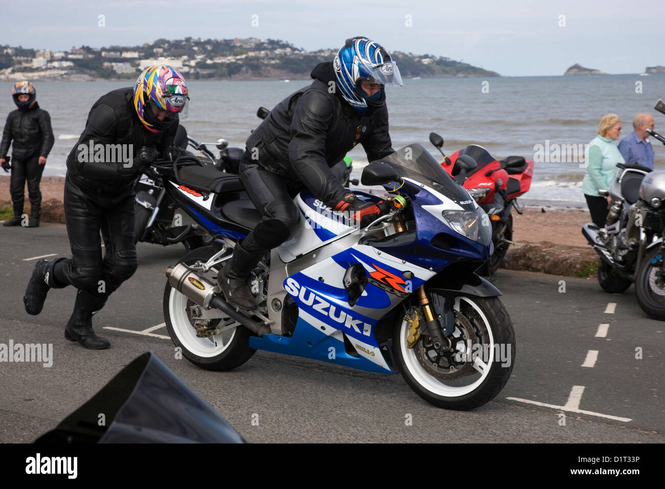Versuch zu springen beginnen ein Motorrad durch drücken es entlang der Straße in Paignton, Devon Stockfoto