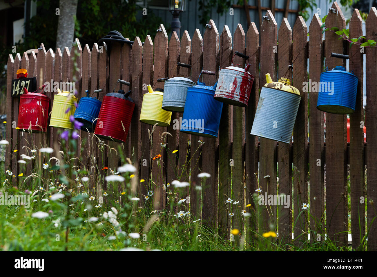 Farbenfrohe Gießkannen werden in Lund, British Columbia, Kanada, dekorativ an einem Holzzaun aufgehängt Stockfoto
