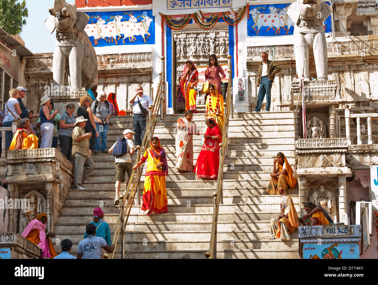 Westliche Touristen sehen indischen Hindhus in bunten Saris der Jagdish Tempel an einem sonnigen Tag in in Udaipur, Rajasthan Indien verlassen Stockfoto