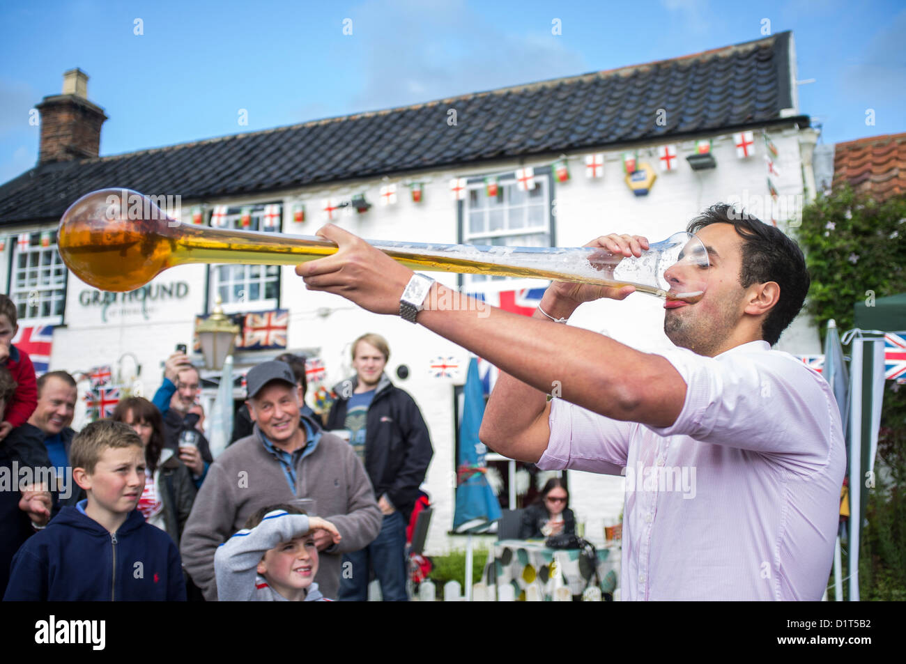 Junger Mann trinken Yard Of Ale im Dorfpub während Queen es Diamond Jubille feiern Stockfoto