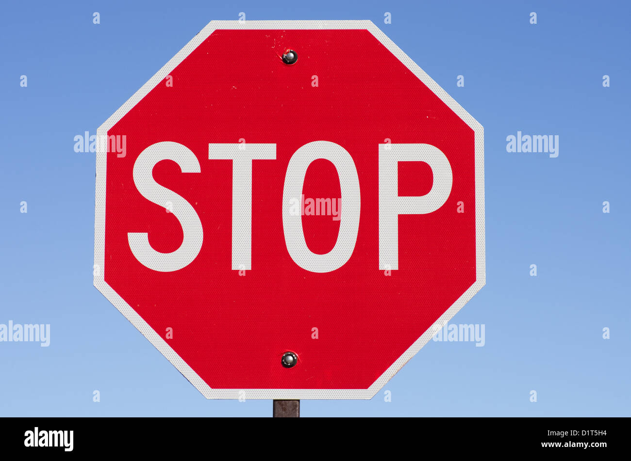 Stop-Schild auf Metallpfosten mit blauem Himmelshintergrund Stockfoto