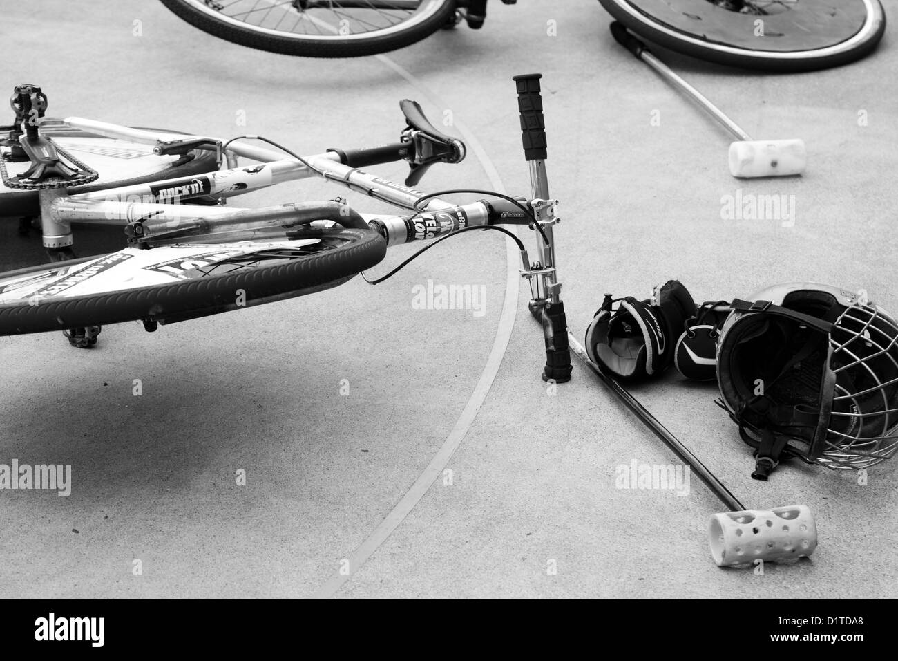 Ein schwarz / weiß Bild eines Fahrrades, das Zement-Gericht mit Helm und Schläger zwischen Bike Polo-Spiele bei einem Tourny Handauflegen. Stockfoto