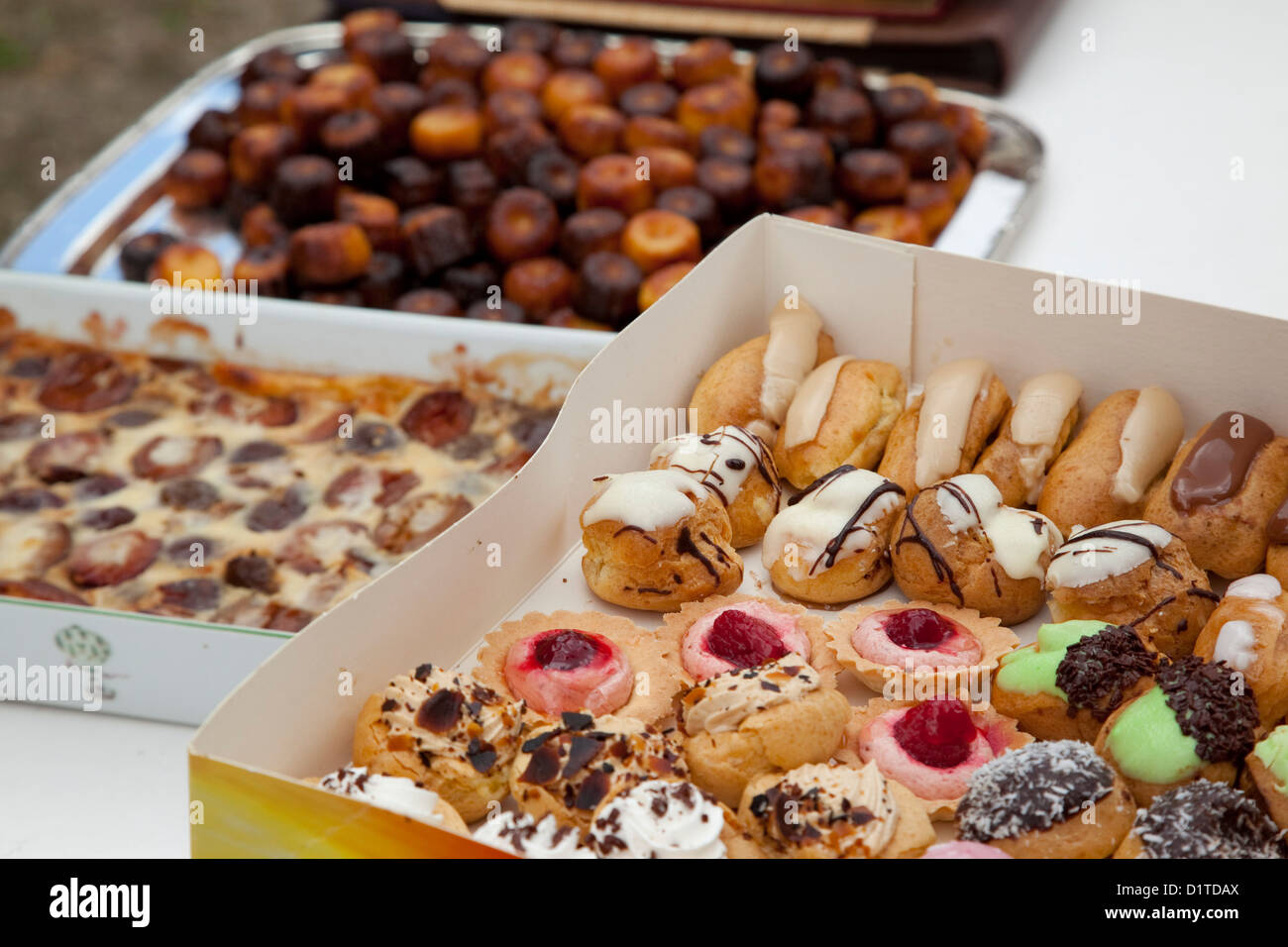 Drei Kisten mit verschiedenen französischen Desserts sitzen auf einem weißen Tisch auf einer Gartenparty. Stockfoto