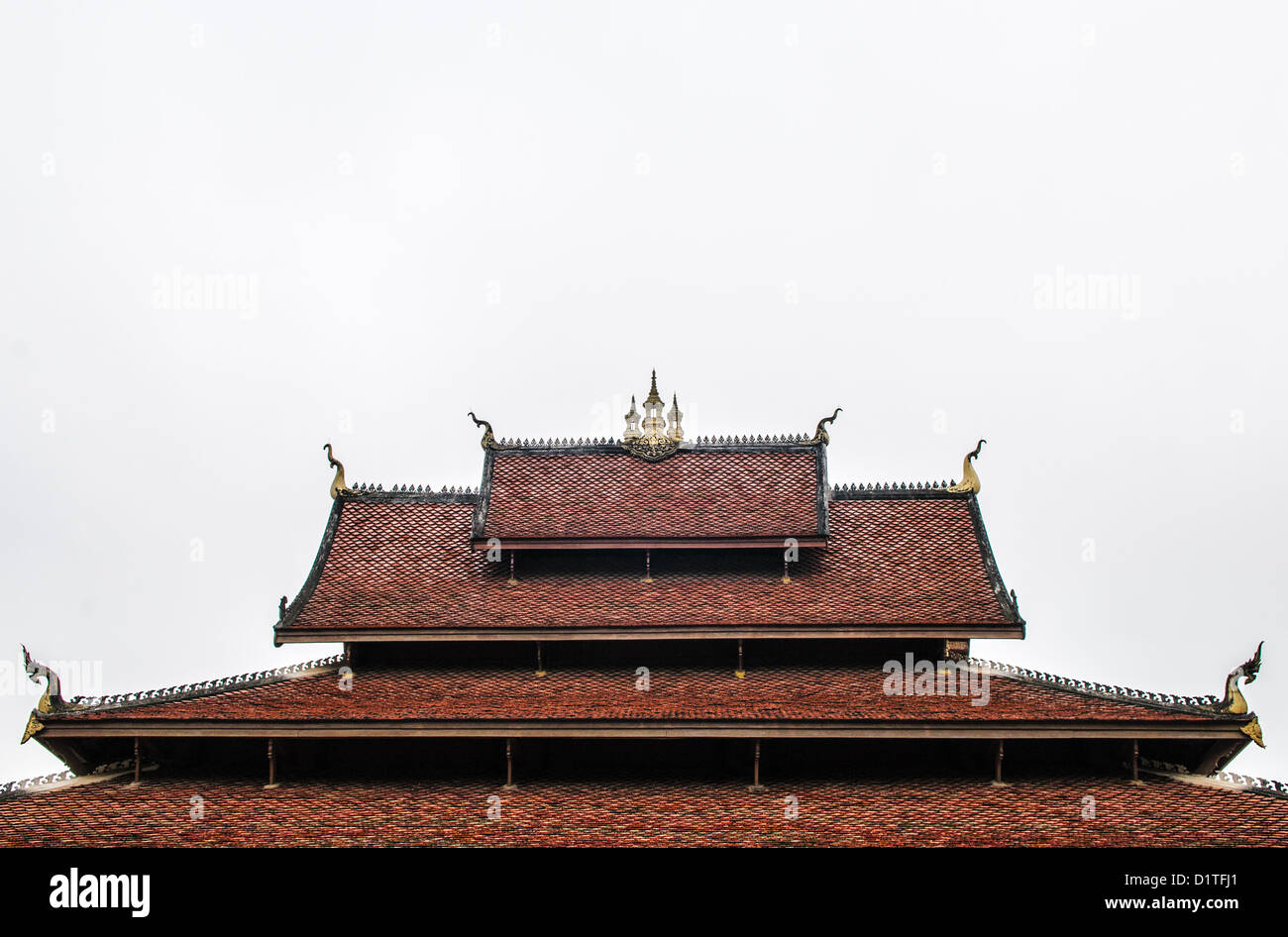 LUANG PRABANG, Laos - Die mehrschichtige, Fliesen- Dach eines Wat (buddhistischer Tempel) in Luang Prabang, Laos, gegen einen bewölkten Himmel. Die Punkte des Daches sind für chofah, eine Darstellung des Garuda, der halb Mensch halb geschmückt - Vogel Fahrzeug Der hindy Gott Vishnu. Stockfoto