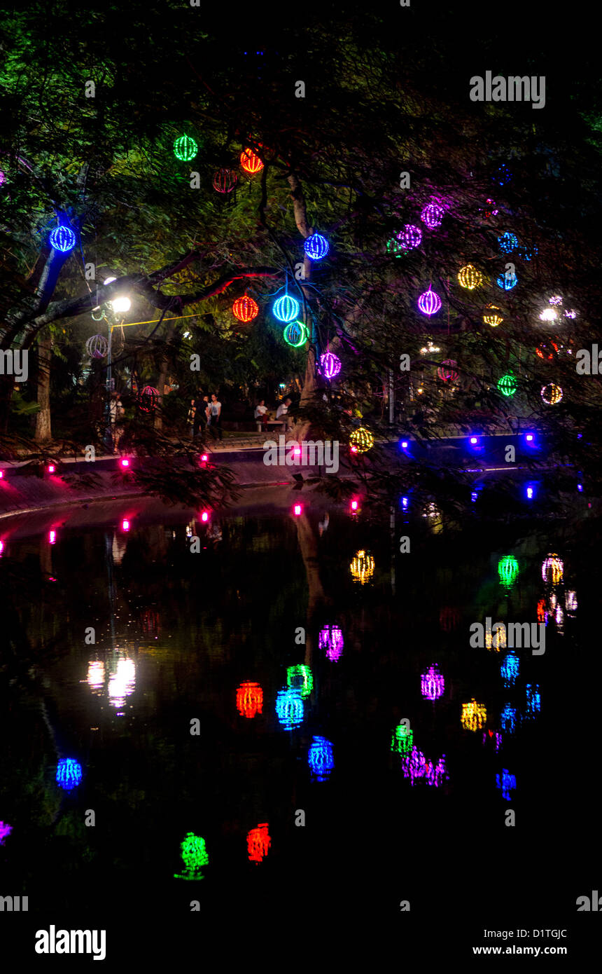Hoan Kiem Lake Dekorative Beleuchtung Hanoi Vietnam // HANOI, Vietnam — farbenfrohe Lichter, die an Reifen Bäumen hängen, erleuchten die nordöstliche Küste des Hoan Kiem Lake im Zentrum von Hanoi. Die dekorative Beleuchtung erzeugt einen Baldachin-Effekt über dem Wanderweg am See. Dieser Abschnitt des Sees grenzt an das historische Viertel der Altstadt. Stockfoto