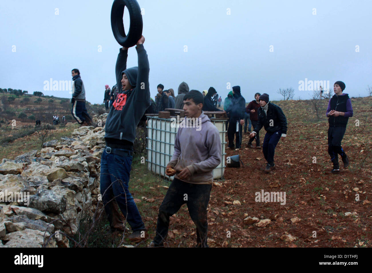 5. Januar 2013 - Nablus, West Bank, Palästina - palästinensische Demonstranten mit Steinen werfen gegen die israelischen Sicherheitskräfte während der Zusammenstöße in den nördlichen Dorf Qusra, südlich von der Stadt Nablus im israelischen besetzten Westjordanland, nachdem jüdische Siedler aus den nahe gelegenen Esh Kodesh Außenposten die Abdeckung des Nebels zu Ansatz Qusra mit dem Ziel der Entwurzelung Dutzende von Olivenbäumen Setzlinge verwendet , aber von palästinensischen Bauern konfrontiert wurden, die Steinen sie, am 5. Januar 2013 warf (Credit-Bild: © Nedal Eshtayah/APA Images/ZUMAPRESS.com) Stockfoto