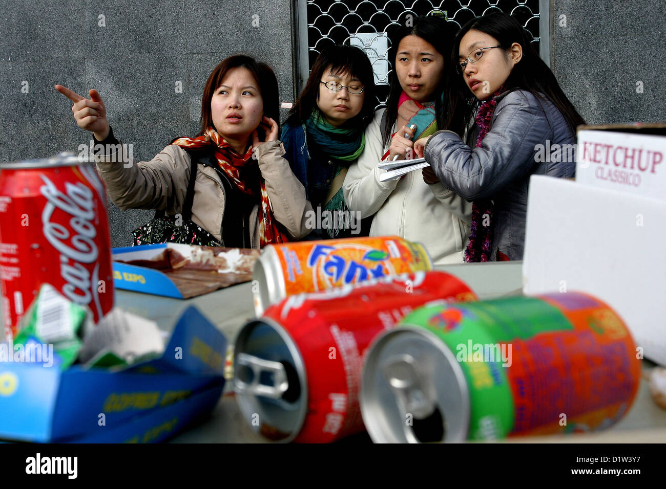 vier asiatische Mädchen vor leeren Dosen Sevilla Spanien Stockfoto