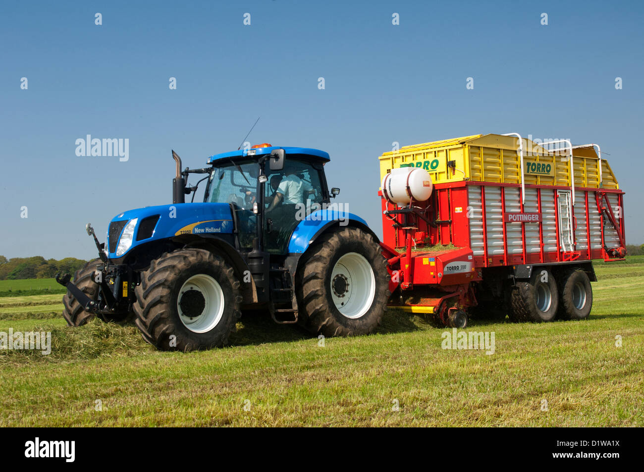 Rasen in Wiese mit einem Pottinger Futter Wagen und New Holland Traktor abholen. Northumberland, UK Stockfoto