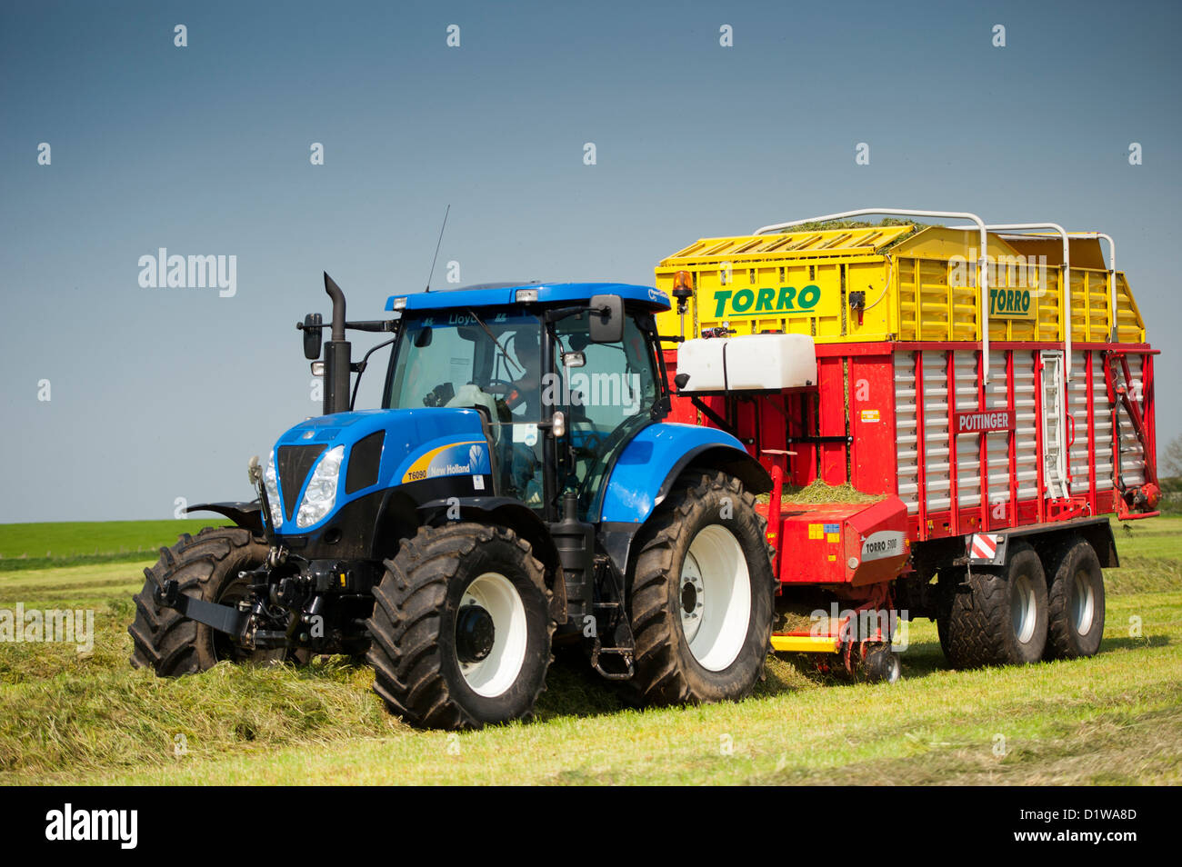 Rasen in Wiese mit einem Pottinger Futter Wagen und New Holland Traktor abholen. Northumberland, UK Stockfoto