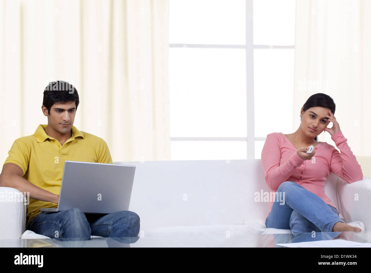 Junge Frau vor dem Fernseher während Mann auf laptop Stockfoto