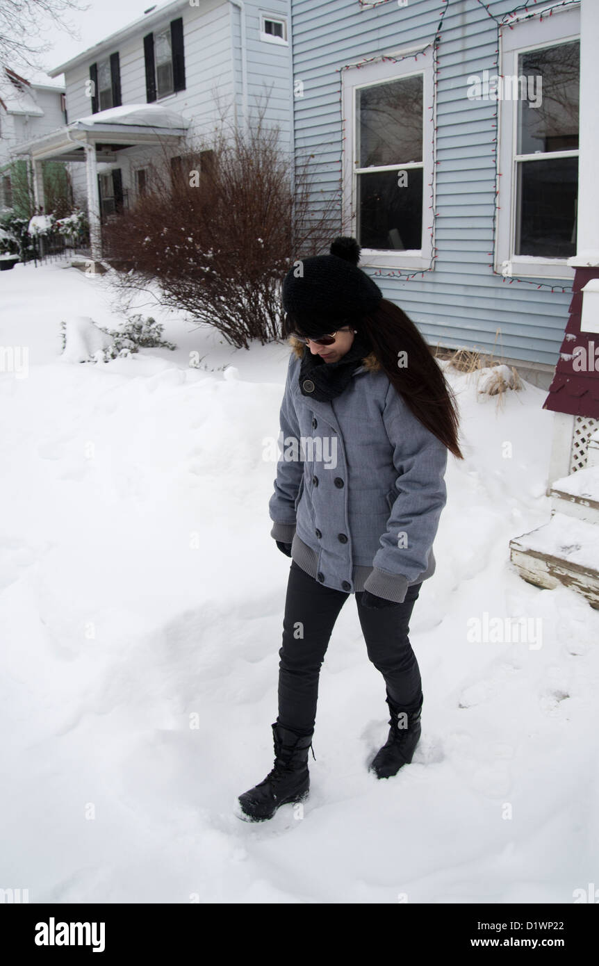 Frau gebündelt gegen den Schnee vor ihrem Haus in ländlichen Ontario, Kanada Stockfoto