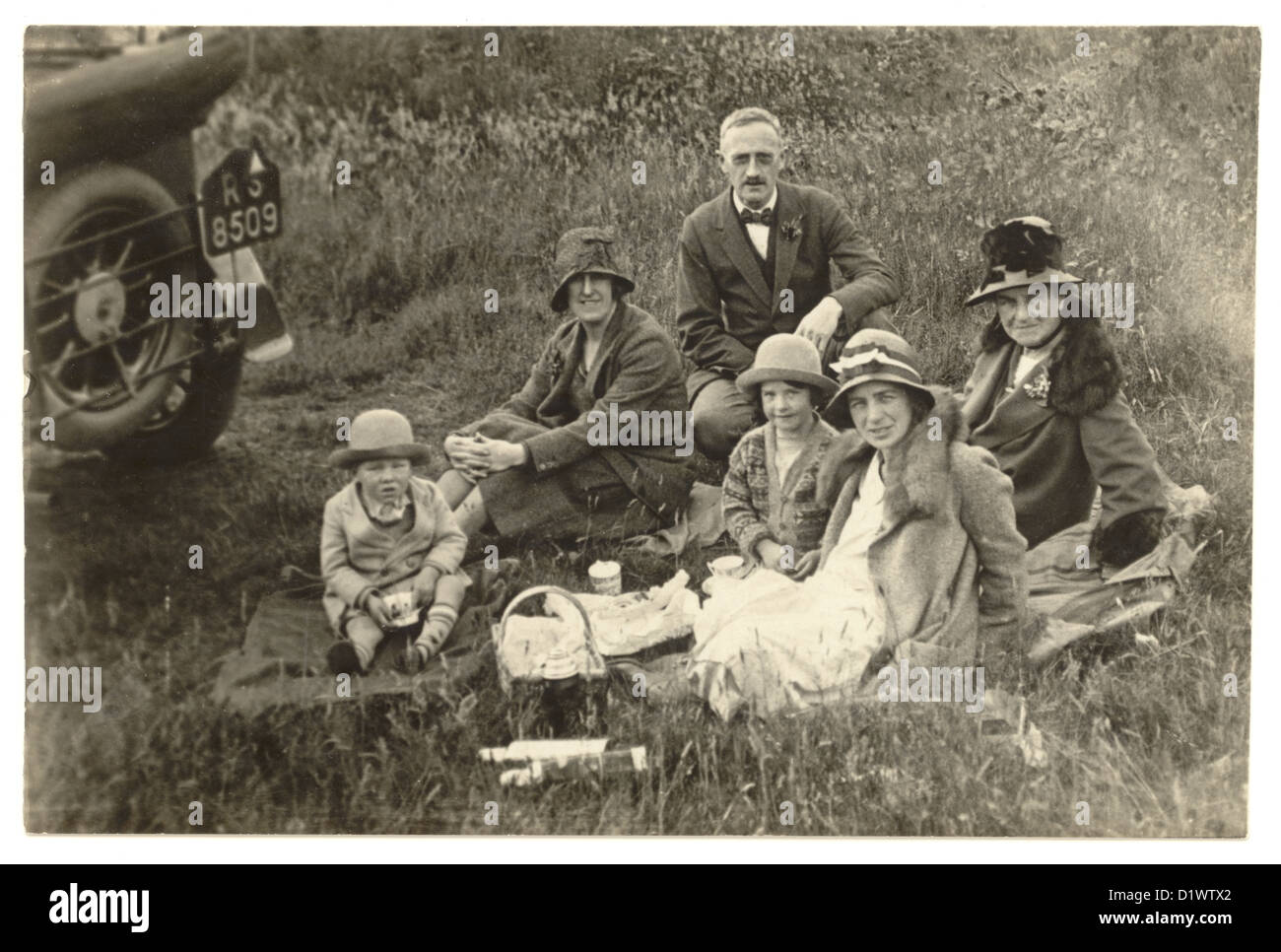 Postkartenfoto der 1920er Jahre von Familiengruppe in ihrer 'Sunday Best' Kleidung bei einem Picknick auf dem Land, Großbritannien Stockfoto