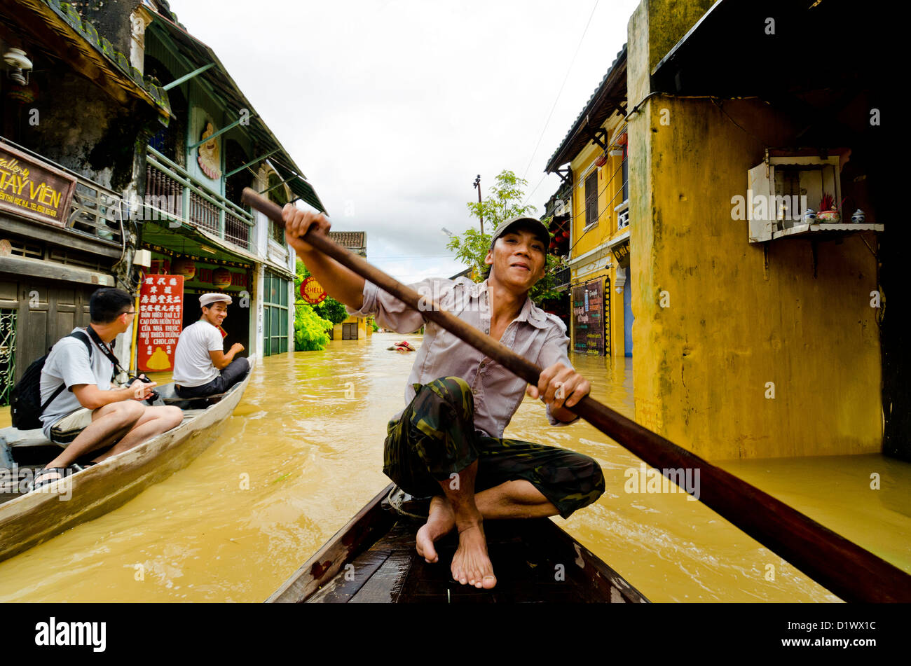 Junge Vietnamesen Mann Ruderboot auf überfluteten Straße, Hoi an ein Stockfoto