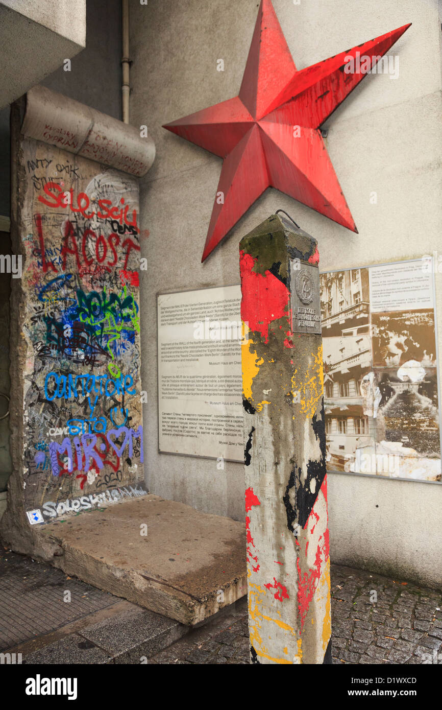 Graffiti auf einem Abschnitt der Mauer mit Informationen, roter Stern und eine original DDR-Grenze post außerhalb Checkpoint Charlie Museum Stockfoto