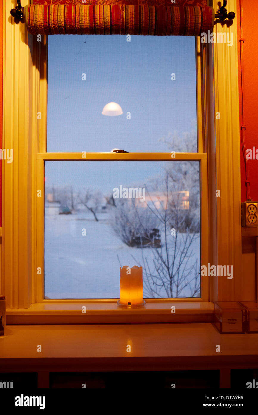 Kerze in das Fenster mit Blick über verschneite Szene in kleinen ländlichen Dorf vergessen Saskatchewan Kanada Stockfoto