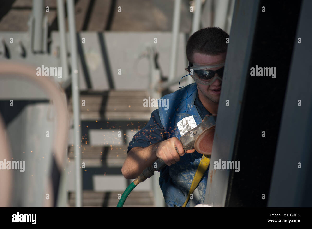 Seaman Lehrling Tyler Grygas aus Rotterdam, N.Y., Rost Sands aus ein Schiebe-Pad-Auge an Bord der Ticonderoga-Klasse geführte Flugkörper Kreuzer USS Mobile Bay (CG-53). Mobile Bay mit der John C. Stennis Strike Group in den USA bereitgestellt wird 5. Flotte Aufgabengebiet Durchführung von maritimer Sicherheitsoperationen, Theater Sicherheitsbemühungen Zusammenarbeit und Unterstützung Missionen für die Operation Enduring Freedom. (7 Januar 2013)  (Foto: U.S. Navy Mass Communication Specialist 2. Klasse Armando Gonzales/freigegeben) Stockfoto