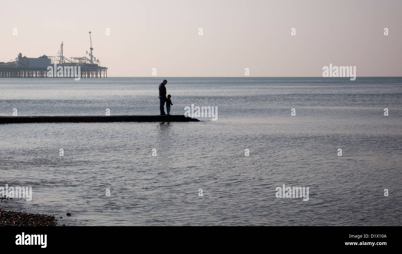 Vater und Sohn auf der Buhne, ruhige See, Pier im Hintergrund stehend ruhiger See Stockfoto