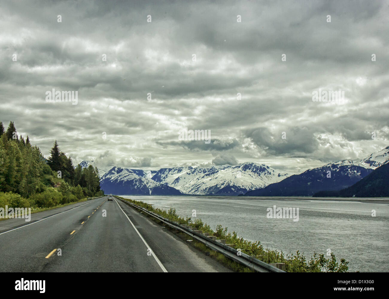 29. Juni 2012 - Halbinsel Kenai, Alaska, USA - Süd, malerische Seward Highway fahren Röcke die Basis der Chugach Mountains [Links] und bietet spektakuläre Ausblicke auf die vergletscherten, schneebedeckten Kenai Mountains eingerahmt von dramatischen Wolkenformationen. Sie steigen in der Ferne über Turnagain Arm--bei Ebbe das Wasser nur über die Bucht. Bezeichnet einen National Forest Scenic Byway, ein All-American Road und eine Alaska Scenic Byway, läuft Seward Highway 127 Meilen [204 km] von Anchorage, Seward, Kenai-Halbinsel, Chugach State Park und Chugach National Forest, ein Schaufenster der natürlichen beau Stockfoto