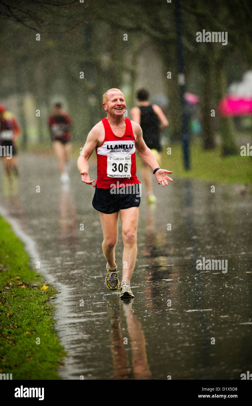 Einen glücklichen Mann mittleren Alters ein 10 k Straße Rennen im Regen, Aberystwyth Wales UK Stockfoto