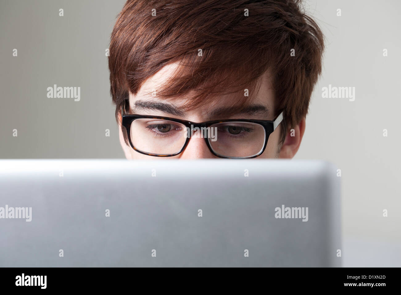 Junger Mann mit Brille, die einem Computer-Bildschirm betrachten. Stockfoto