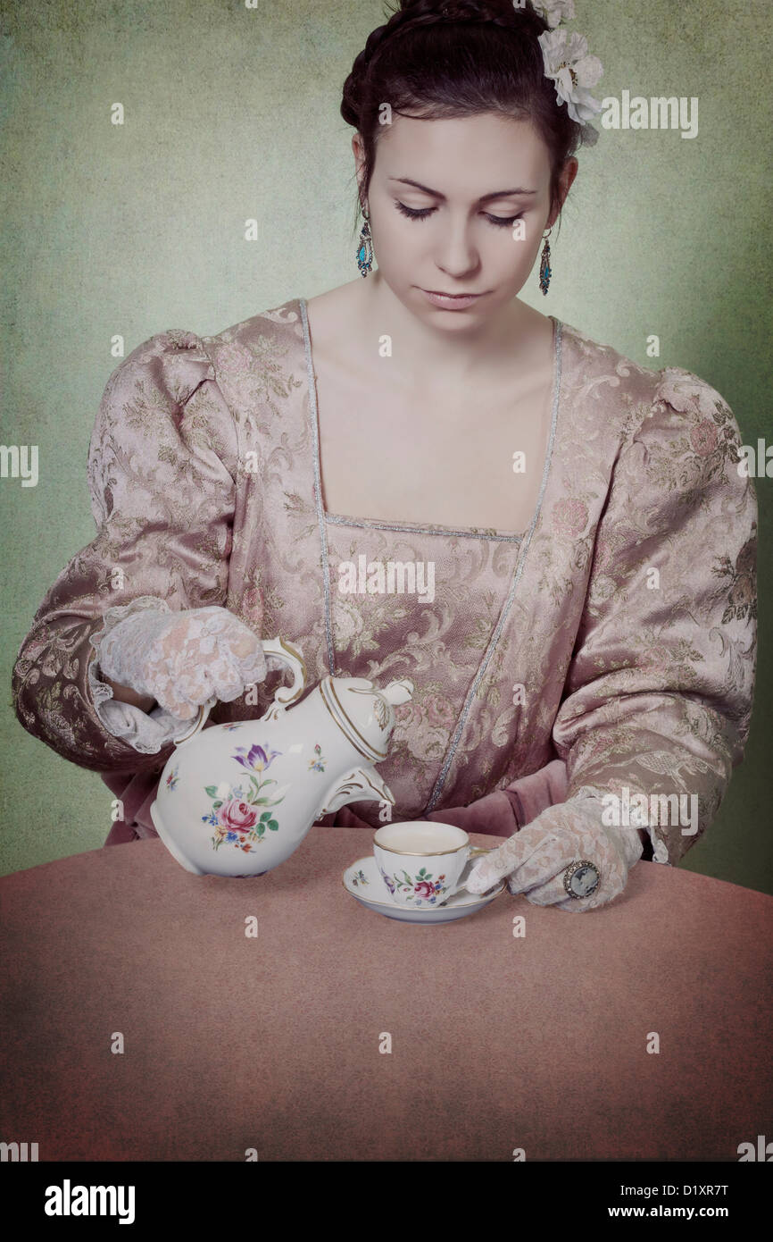 eine Frau in einem Zeitraum Kleid ist Kaffee in eine Tasse Gießen. Stockfoto