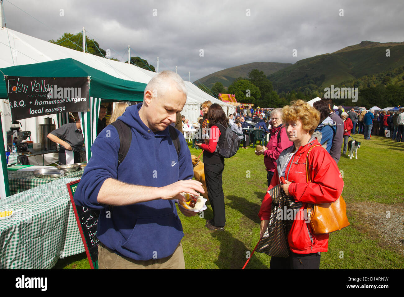 Menschen etwa einen Hot Dog in Grasmere Lakeland Sport, Nationalpark Lake District, Cumbria, England zu essen. Vereinigtes Königreich Stockfoto