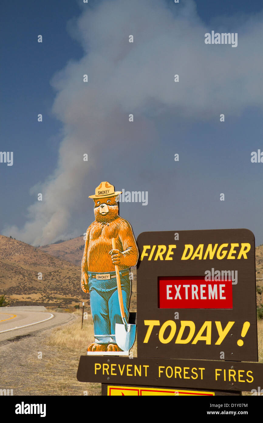 Smokey Bear extreme Feuer Warnschild mit einer Wolke aus Rauch von einem Waldbrand im Hintergrund in Boise County, Idaho, USA. Stockfoto