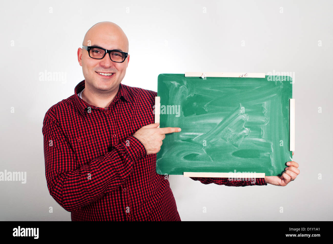 Junge Erwachsene Glatzkopf mit Brille hält eine kleine grüne Tafel. Stockfoto