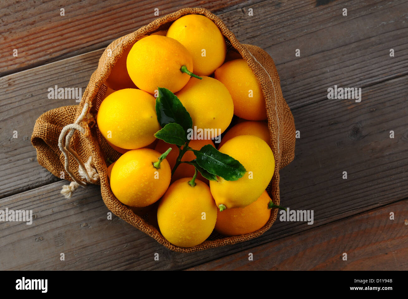 Draufsicht auf einen Leinensack gefüllt mit frisch gepflückten Zitronen auf einem rustikalen Holz Hintergrund. Querformat mit Textfreiraum. Stockfoto