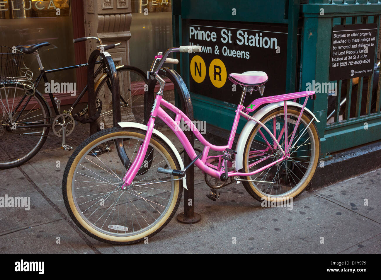 Hell rosa Frau Fahrrad angekettet an einem Fahrradständer in der Nähe von u-Bahnstation in New York City Stockfoto