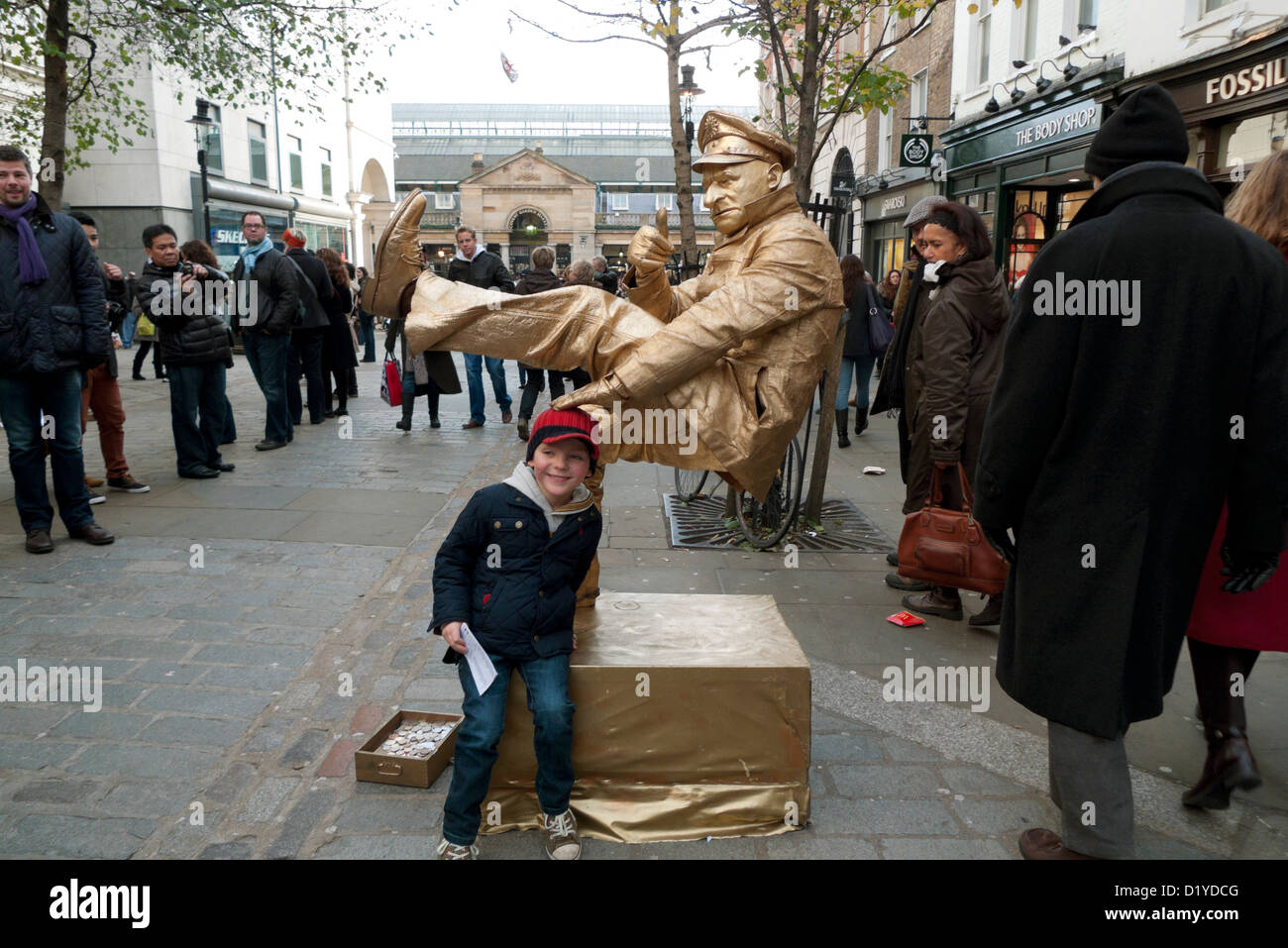 Ein junger Junge in der Crowd Street, der einen Straßenkünstler in Covent Garden, London, England, UK, mit goldener Farbe bemalt SAH, KATHY DEWITT Stockfoto