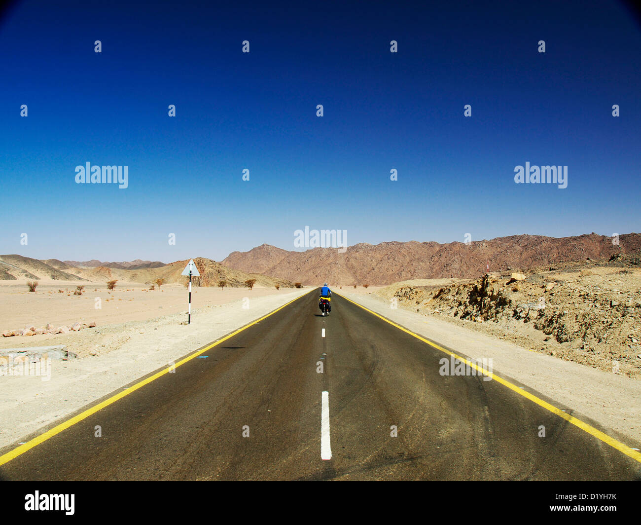 Ein einsamer Radfahrer auf einer neuen Asphaltstraße in Sudan. Reisen von Wadi Halfa nach Dongola Stockfoto