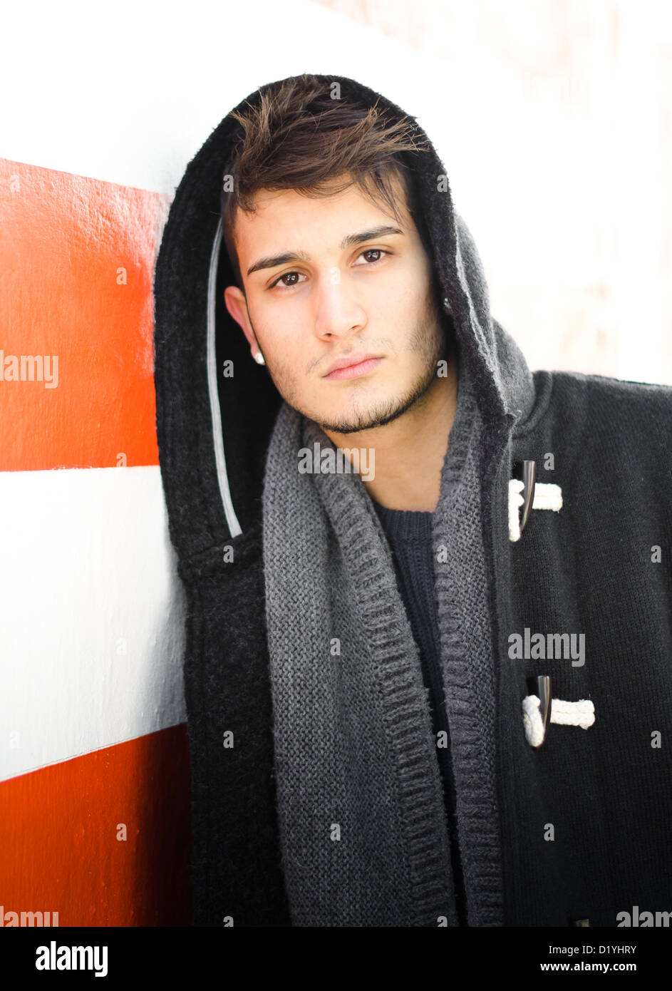 Gut aussehender junger Mann in Hoodie weiß und orange gestreifte Wand Stockfoto