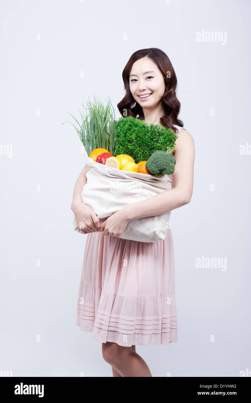 Eine Frau im Kleid hält einen Beutel mit Gemüse Stockfoto