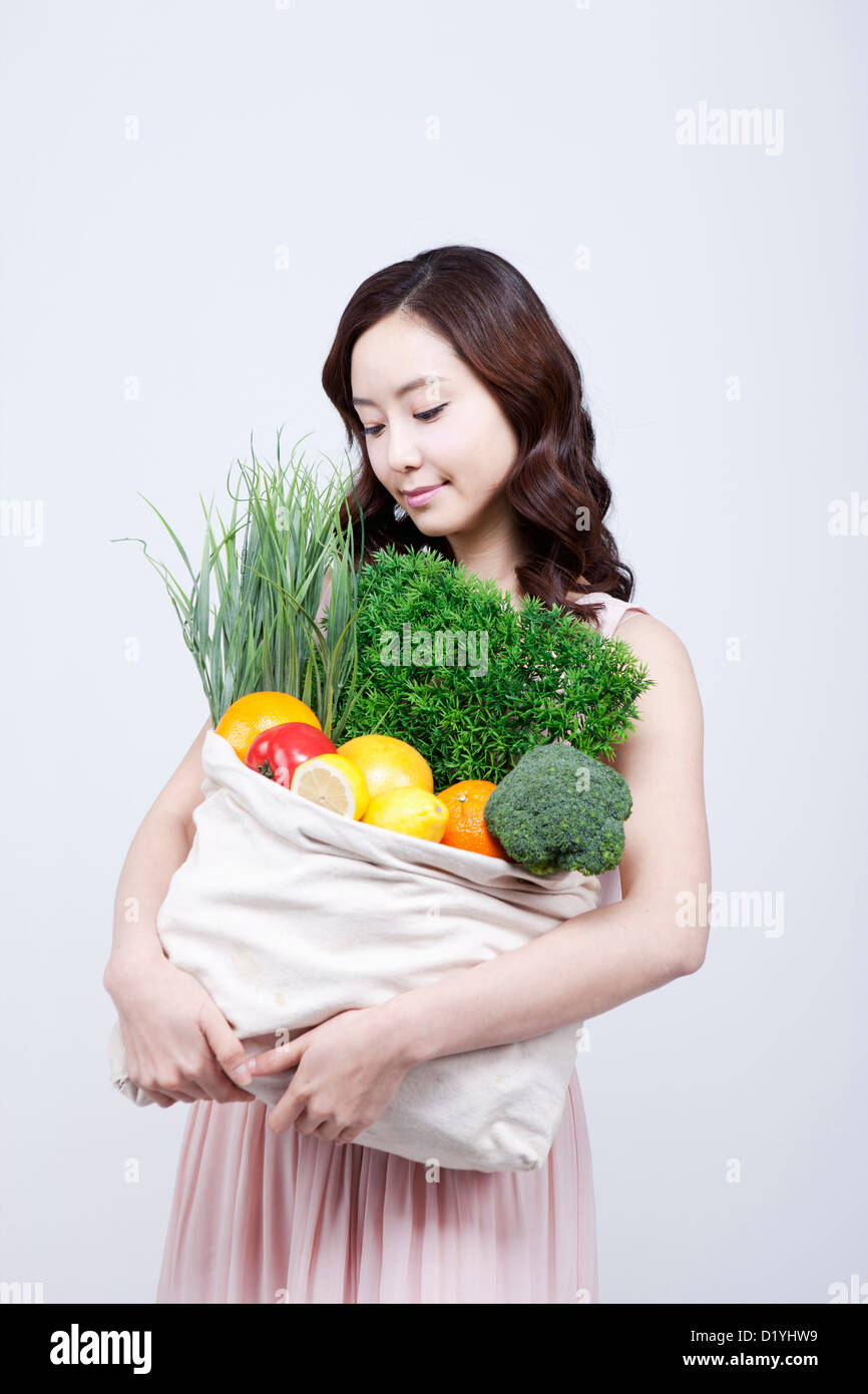 Eine Frau im Kleid betrachten einen Beutel mit Gemüse in die Arme Stockfoto