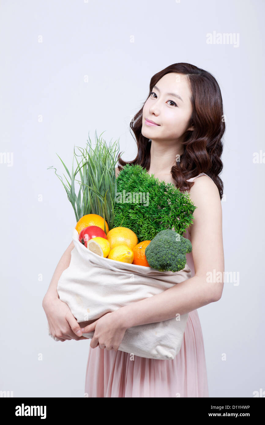 Eine Frau im Kleid hält einen Beutel mit Gemüse Stockfoto