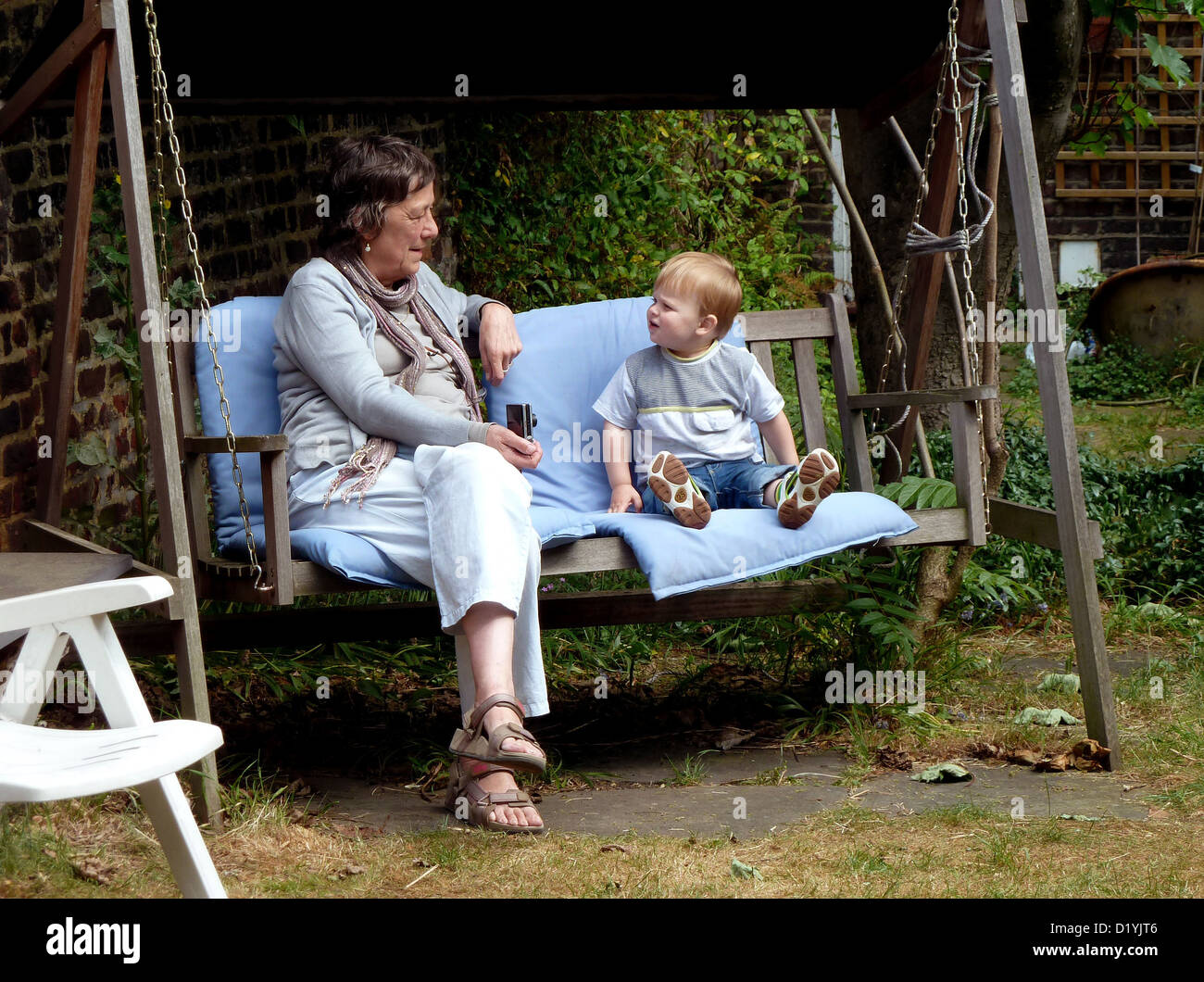 Großmutter mit Enkel beim Sitzen auf einem Stuhl Gartenschaukel Stockfoto