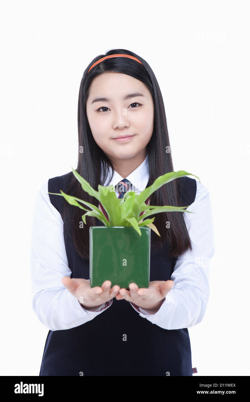 eine Studentin tragen Schuluniform hält ein Blumentopf Stockfoto