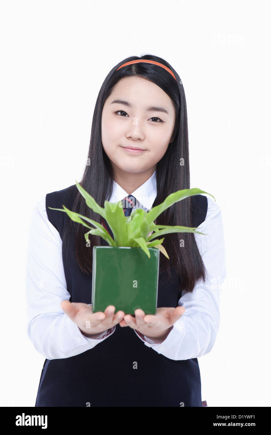 eine Studentin tragen Schuluniform hält ein Blumentopf Stockfoto
