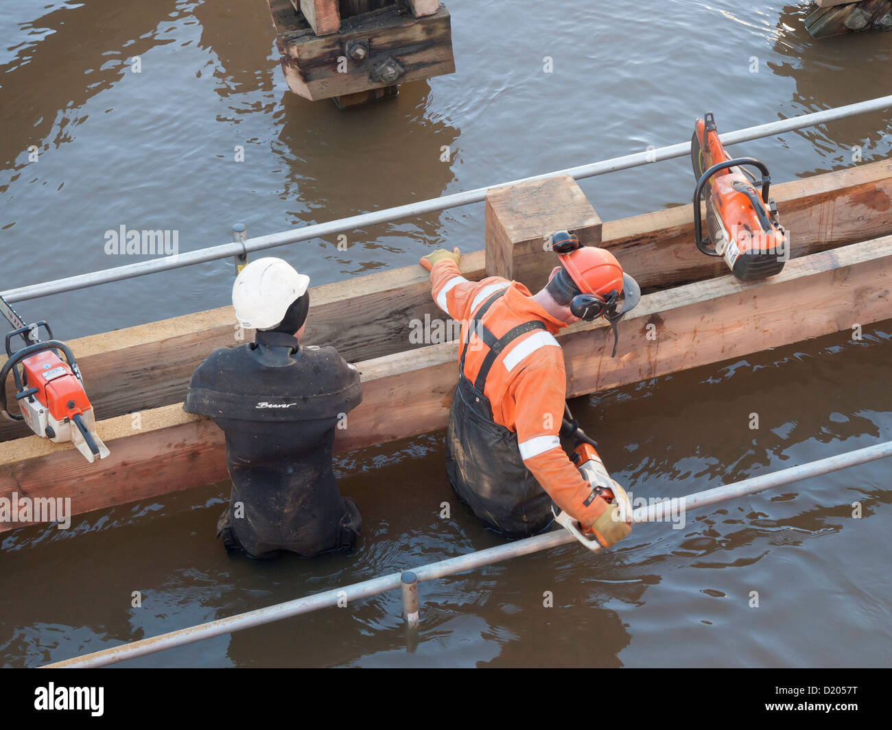 Männer stehen in tiefem Wasser bohren Bolzen für neue Holz-Kotflügel für den Schutz von Whitby swing Bridge von Schiffskollision Stockfoto