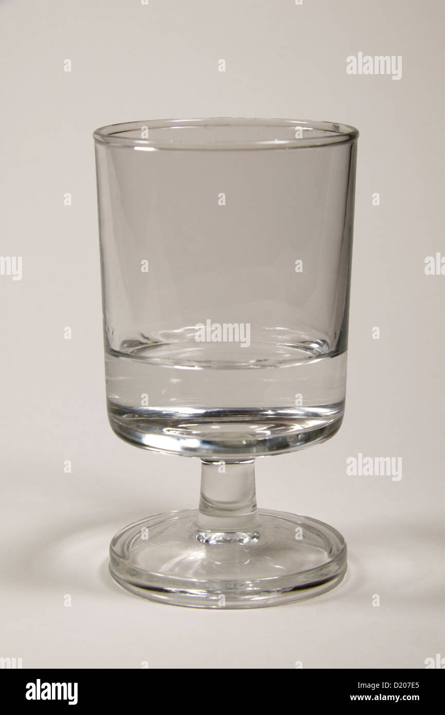 Ein Glas Becher, enthält eine kleine Menge Wasser. Stockfoto