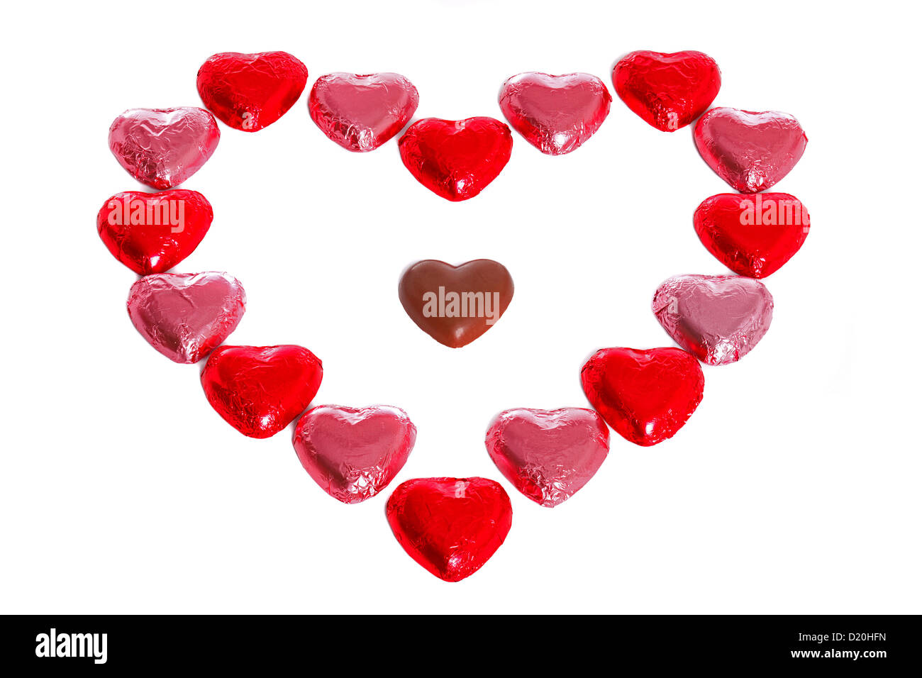 Ein Herz aus Folie eingewickelt Pralinen mit einer in der Mitte, weißer Hintergrund ausgepackt. Stockfoto
