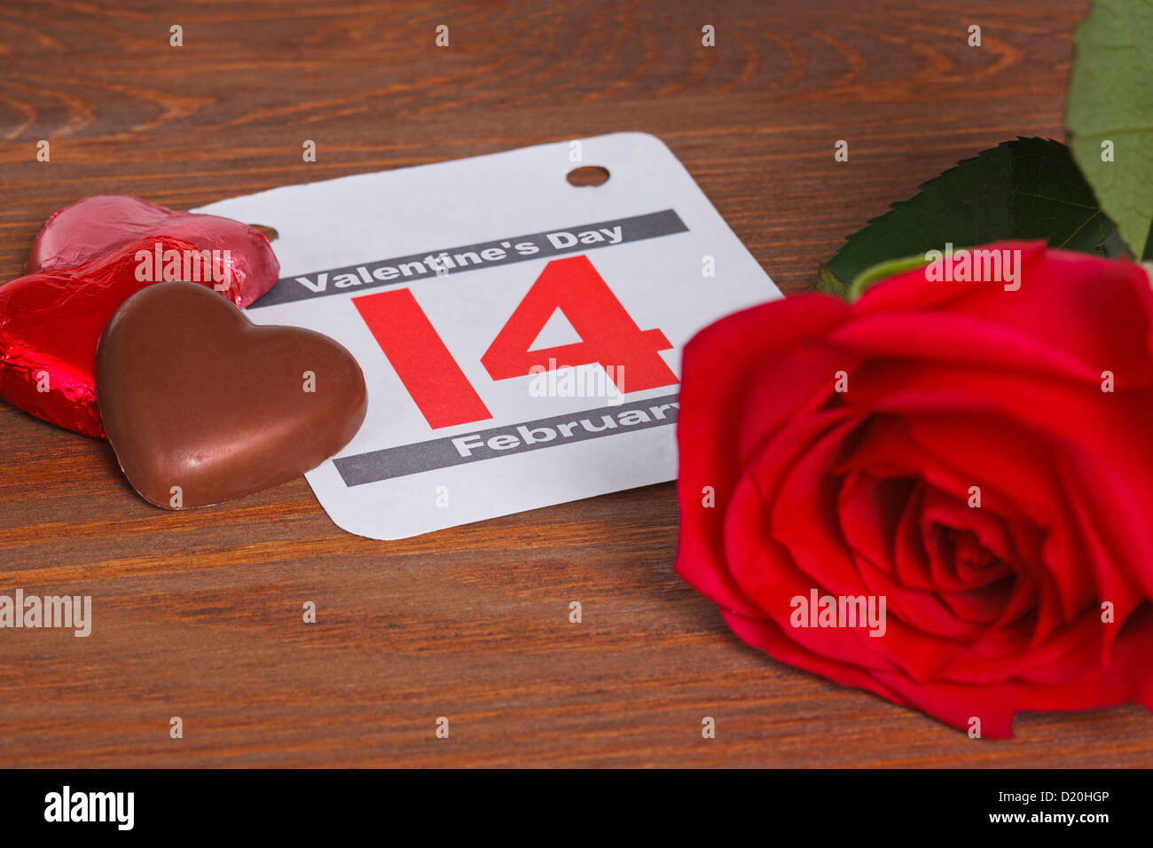 Valentinstag-Stillleben-Foto mit einem Kalenderdatum für den 14. Februar mit einer einzelnen roten Rose und Herz geformt Pralinen Stockfoto